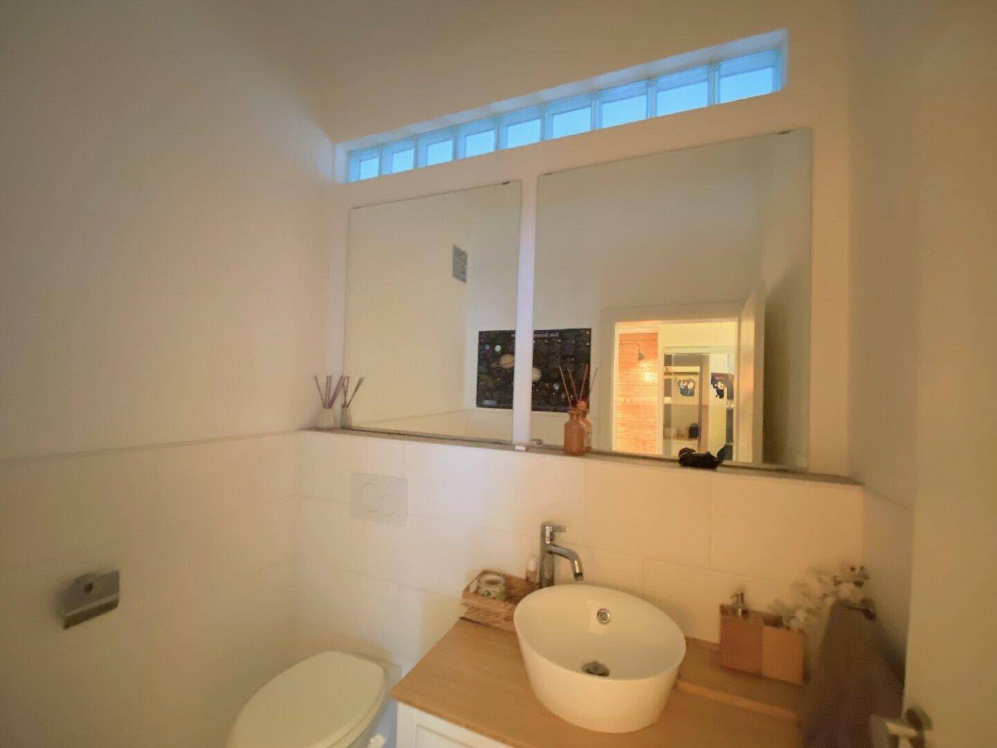 Kleines Gäste-WC mit modernem Waschbecken, Spiegelfläche und Oberlichtfenster.
