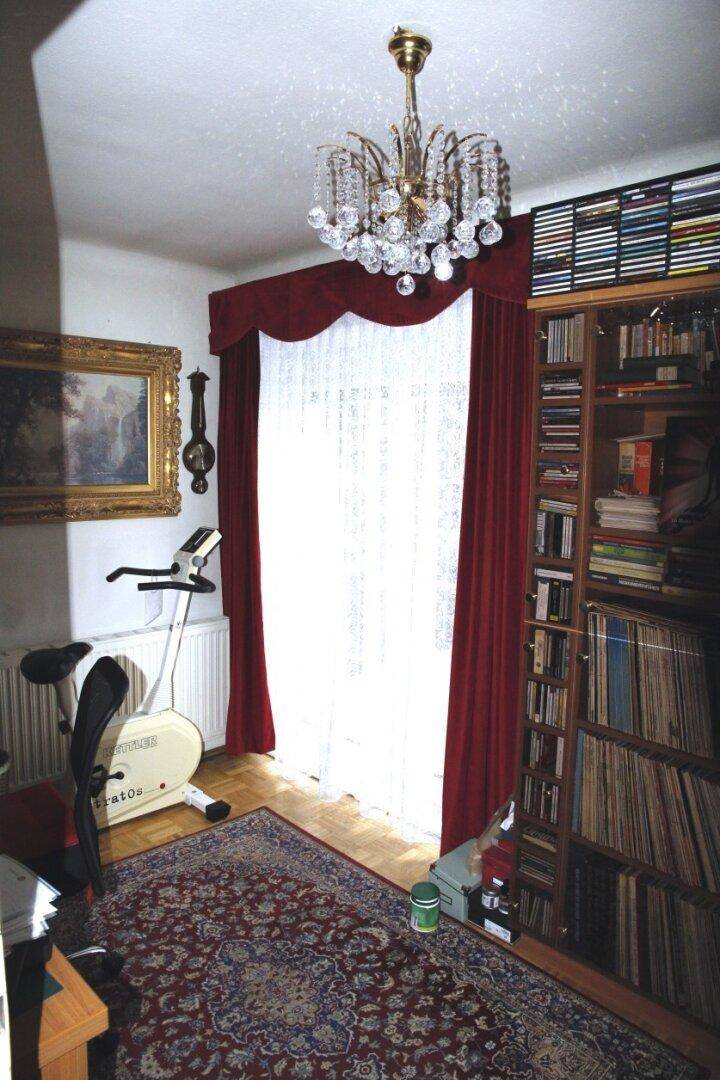 Arbeitszimmer mit großem Bücherregal, Schreibtisch und Heimtrainer, klassisch eingerichtet.