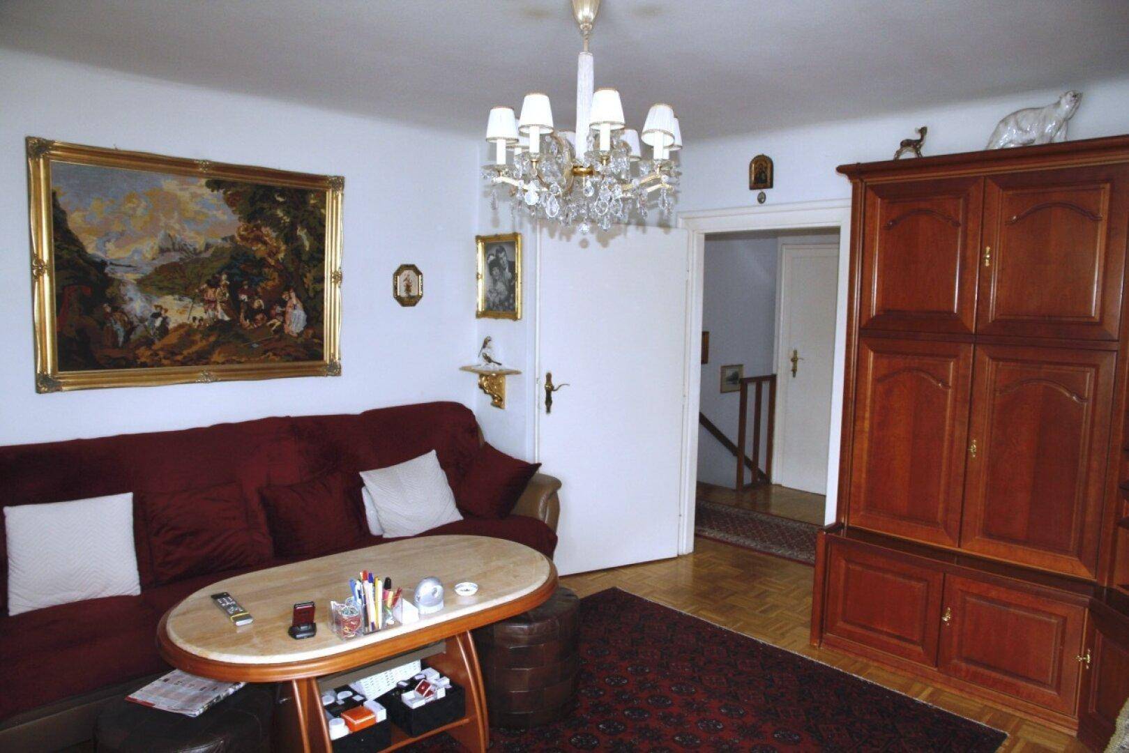 Wohnzimmer mit rotem Sofa, Holzboden und klassischer Einrichtung, ideal zum Entspannen.