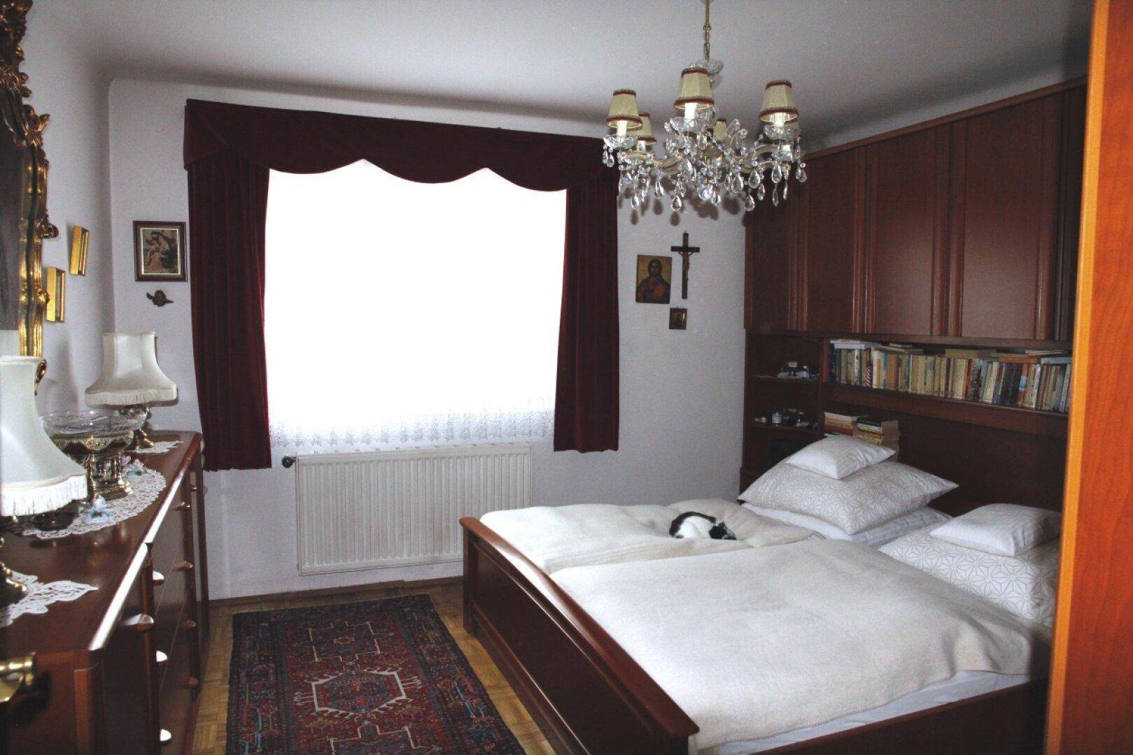 Schlafzimmer mit Doppelbett, Einbauschränken und großem Fenster, klassisch eingerichtet.