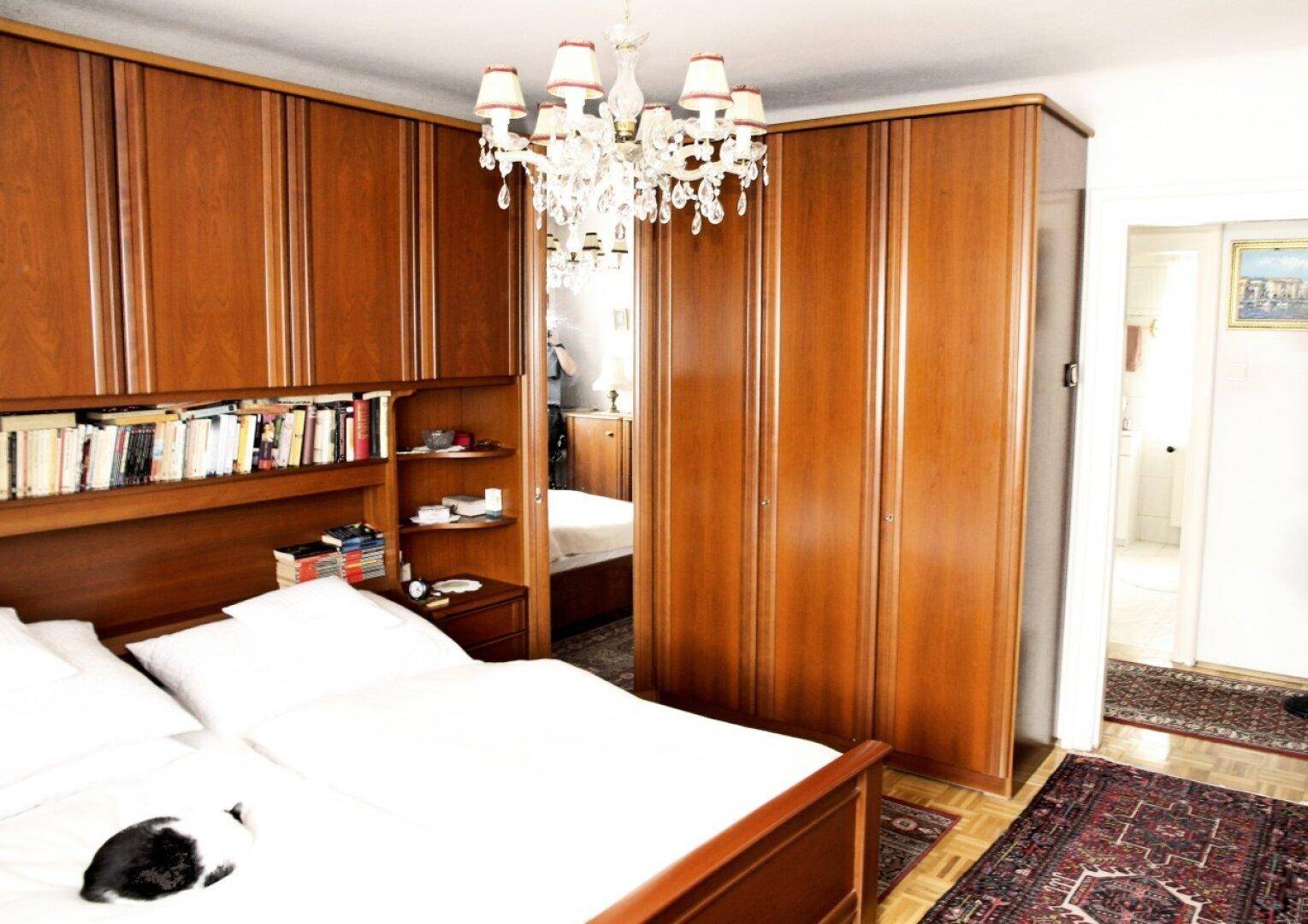 Schlafzimmer mit Doppelbett, integrierten Holzschränken und Parkettboden.