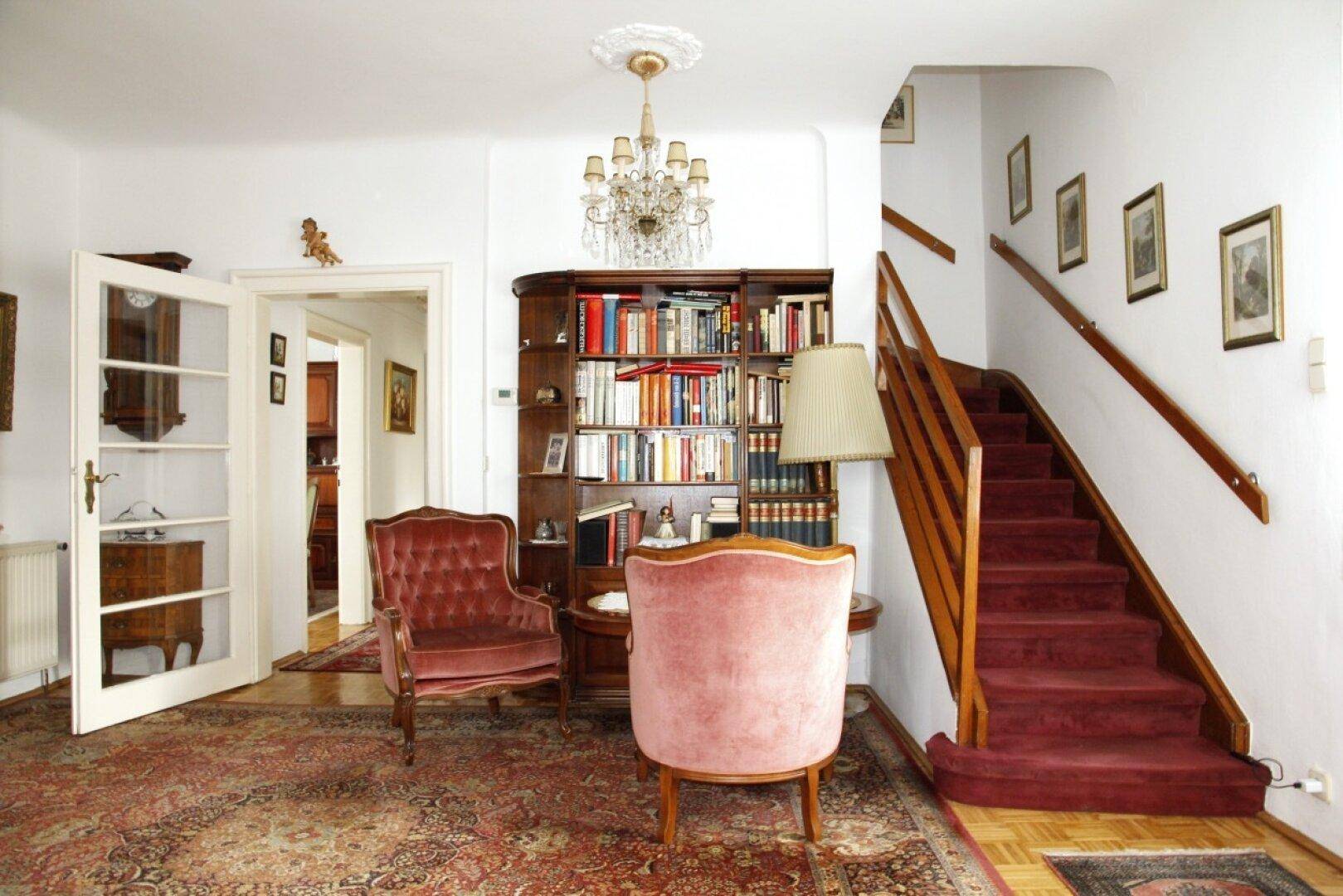 Heller Flur mit Holztreppe, Bücherregal und gemütlicher Sitzecke, klassisch eingerichtet.