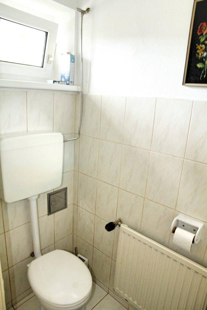 Kleines WC mit Fenster, Toilette und Heizkörper, einfach und funktional.