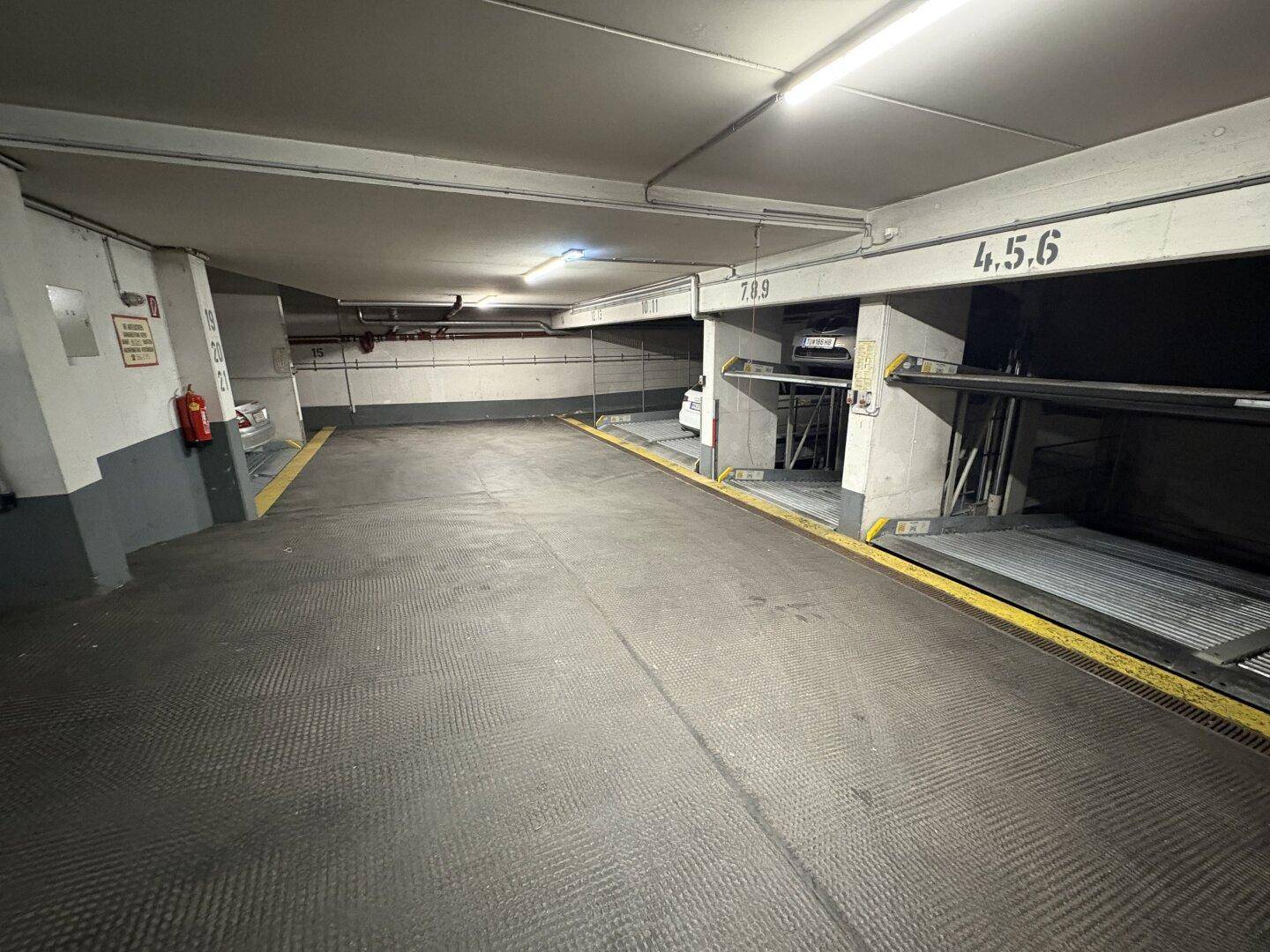 Geräumige Tiefgarage mit mehreren mechanischen Parksystemen und Betonwänden.