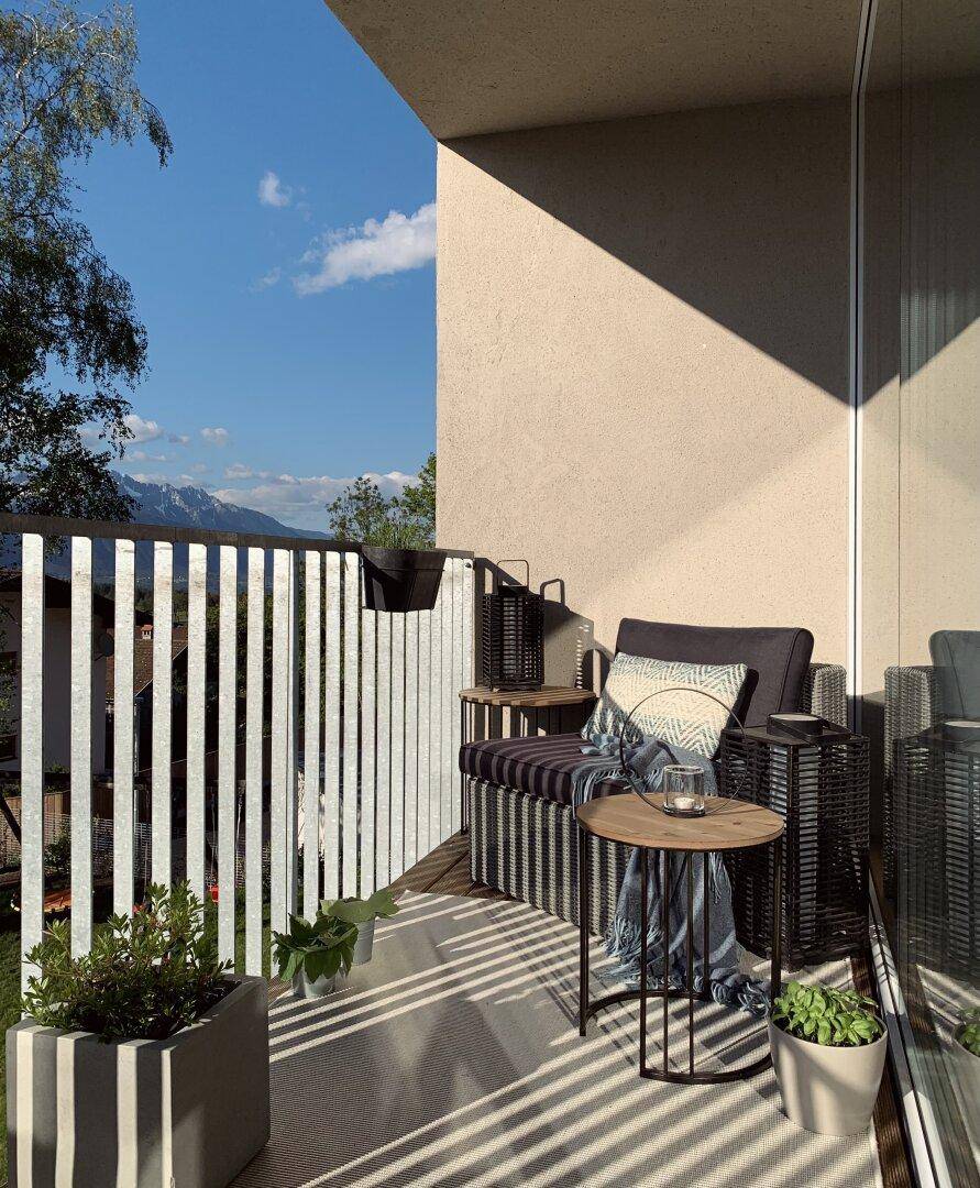 Gemütlicher Balkon mit Sitzgelegenheiten, Pflanzen und einem weiten Blick auf die Berge.
