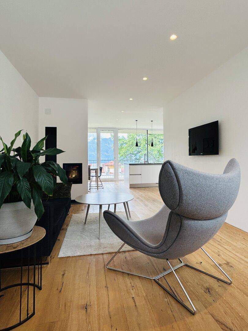 Helles Wohnzimmer mit modernem Sessel, Holzboden und einem gemütlichen Kaminbereich.