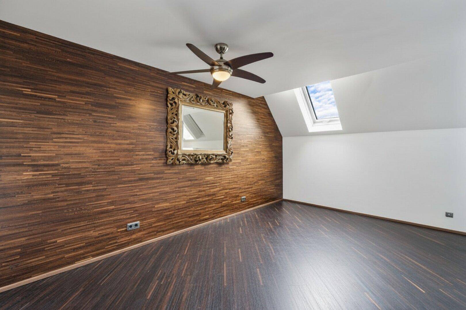 Geräumiger Raum mit Holzwandverkleidung, Dachfenster und Deckenventilator.
