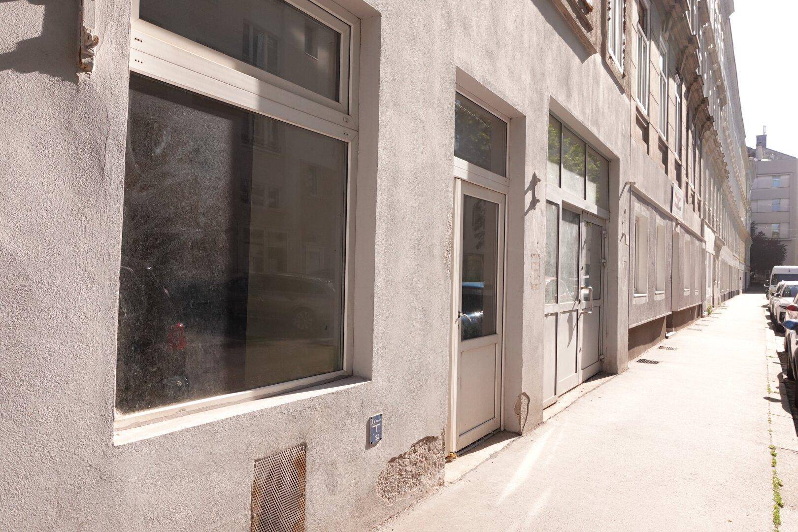Fassade eines Gebäudes an der Straße mit mehreren Fenstern und Eingangstüren, in hellem Putz.