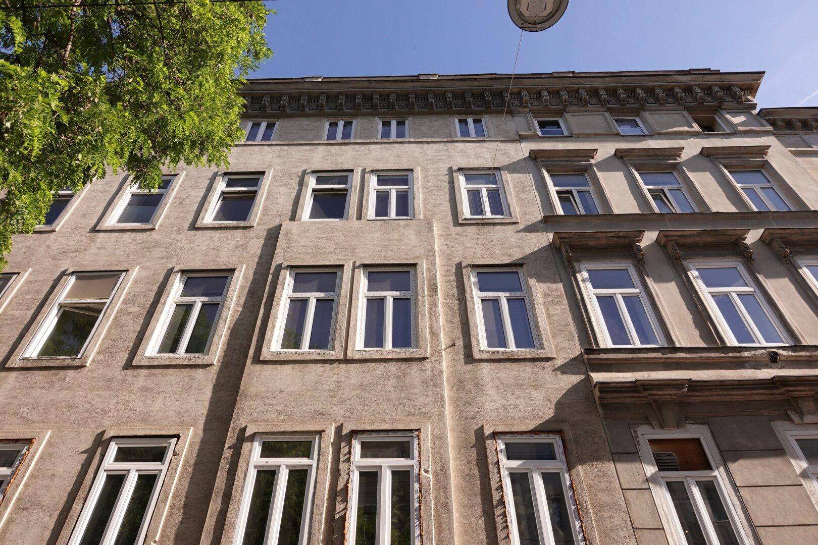 Blick nach oben auf die Fassade eines Altbaus mit zahlreichen Fenstern und klassischer Architektur.