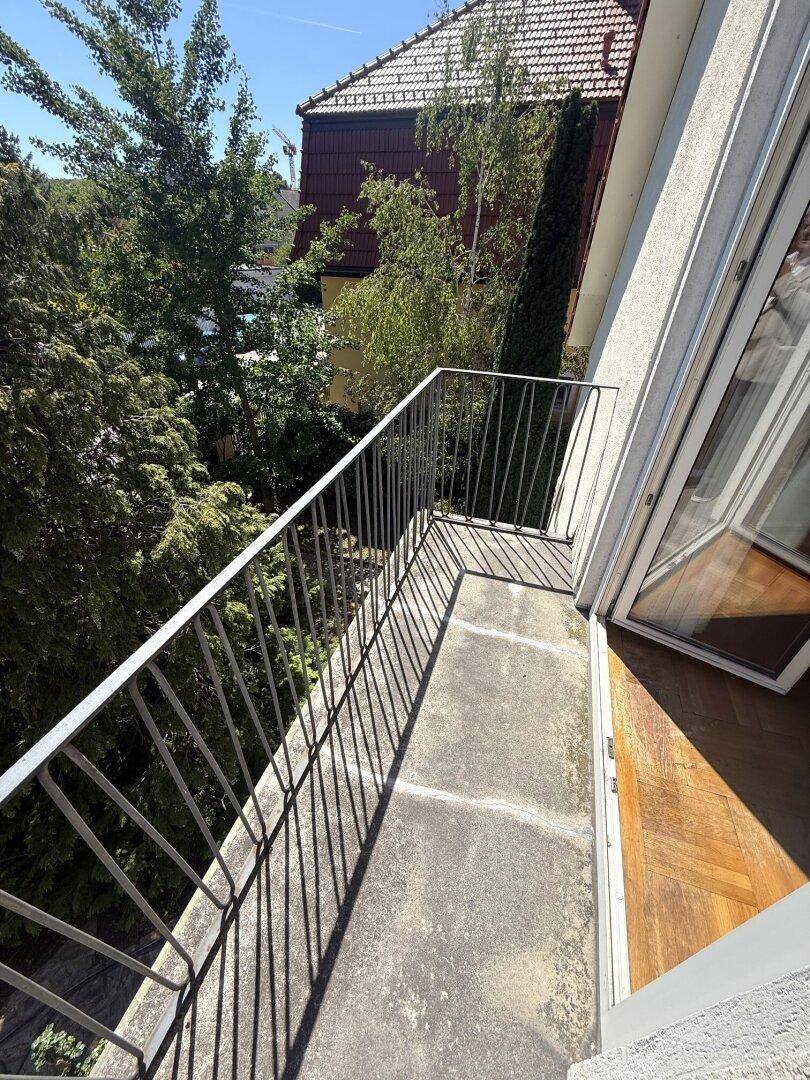 Kleiner Balkon mit Metallgeländer und Blick ins Grüne.