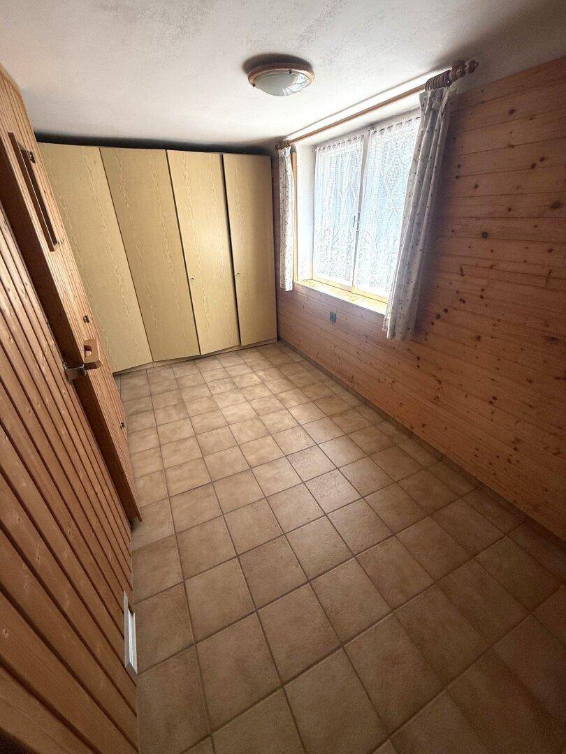 Zimmer mit Fliesenboden, Holzvertäfelung und Einbauschränken.
