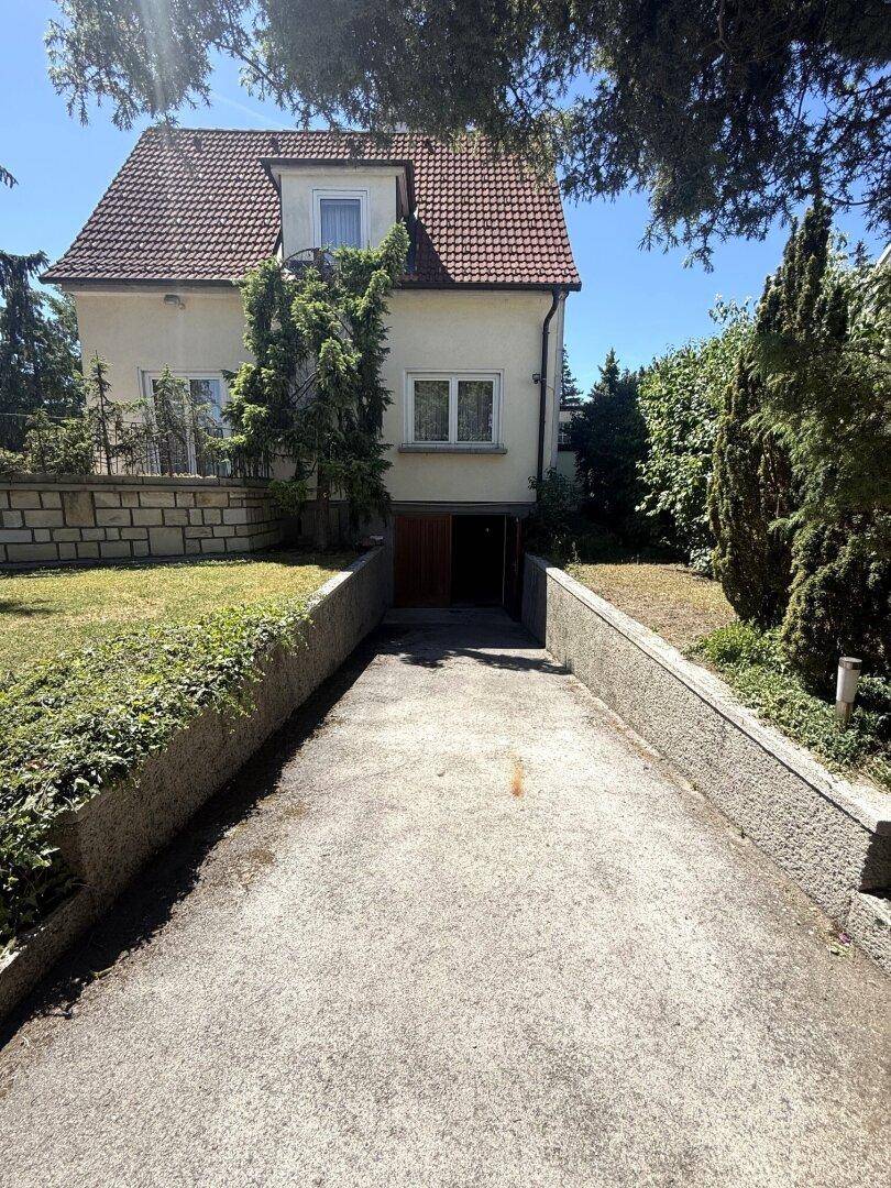 Vorderansicht des Hauses mit Zufahrt zur Tiefgarage und gepflegtem Vorgarten.