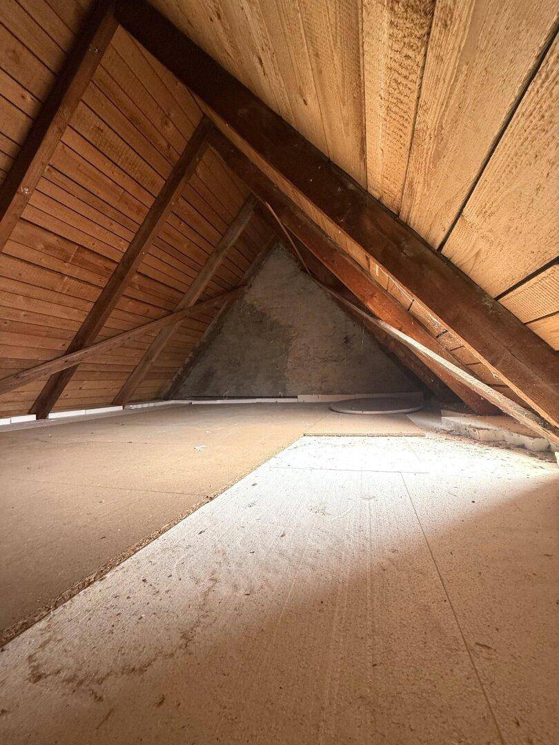 Unausgebauter Dachboden mit sichtbaren Holzbalken und Dachschrägen, bereit für den Ausbau.