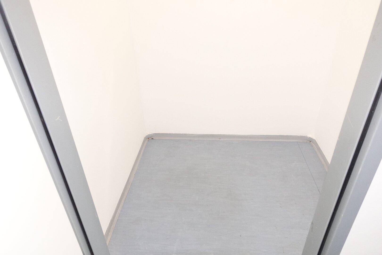 Kleiner, leerer Raum mit grauem Boden und weißen Wänden, möglicherweise als Abstellraum nutzbar.