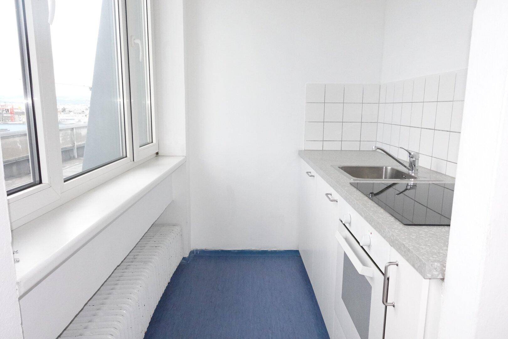 Kleine, funktionale Küchenzeile mit Spüle, Kochfeld und Backofen, ideal für kompaktes Wohnen.