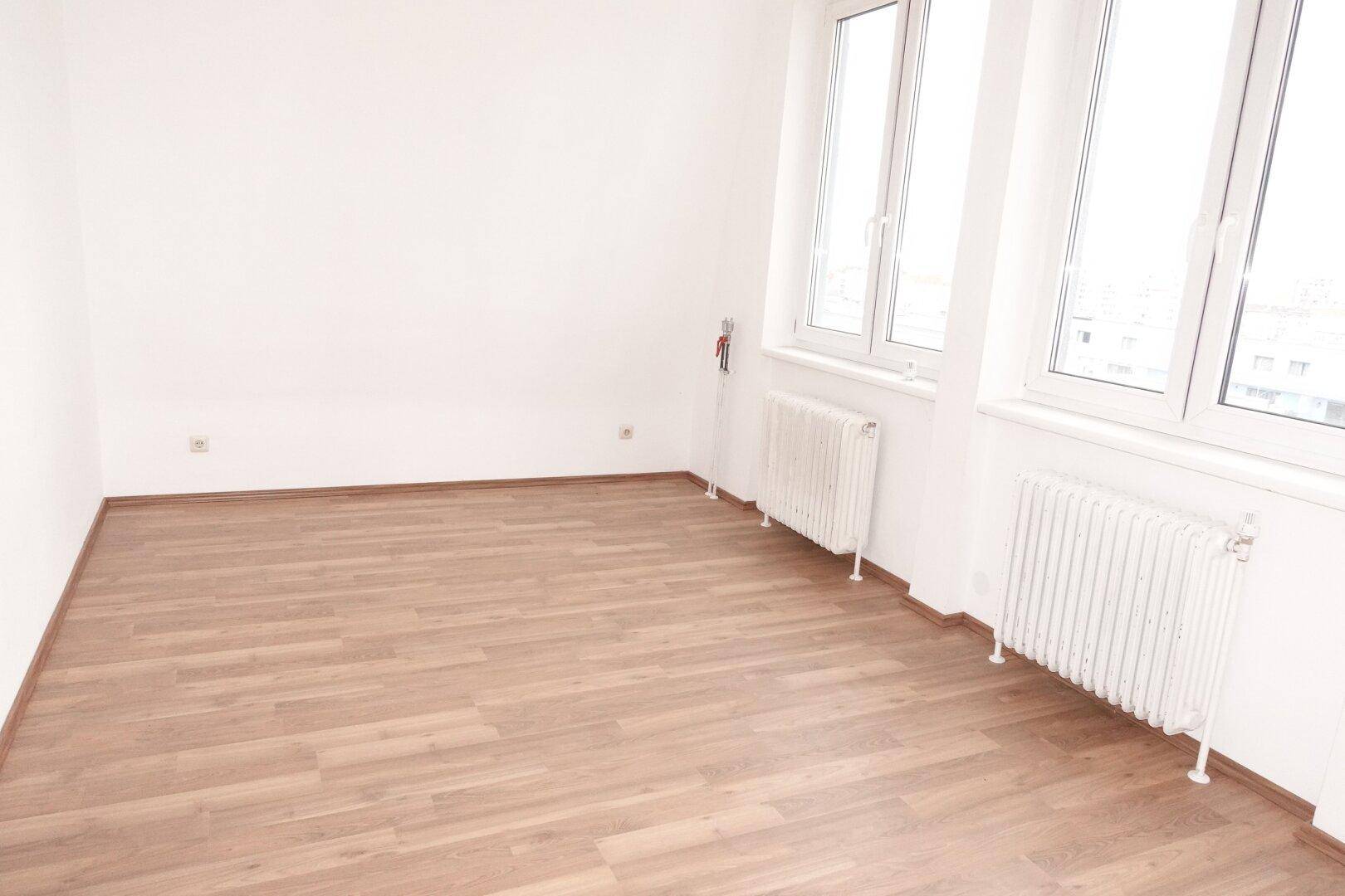 Helles Zimmer mit Laminatboden und großen Fenstern, die viel natürliches Licht hereinlassen.