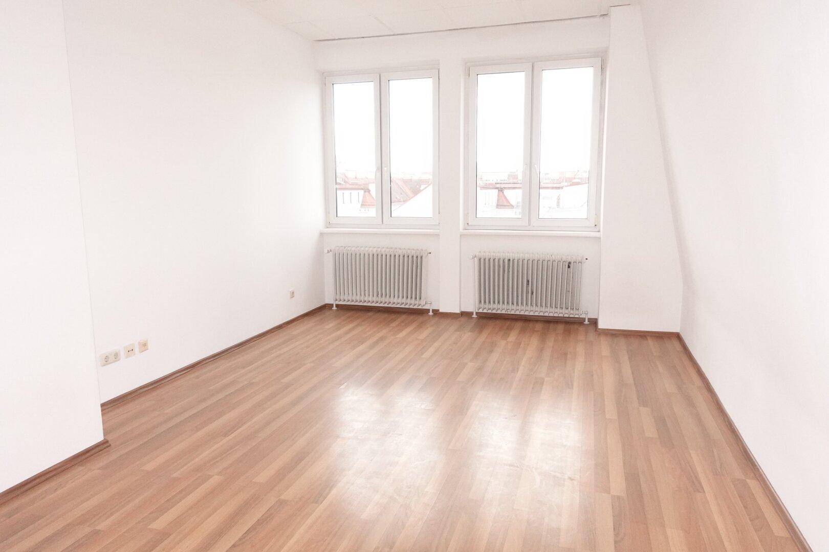 Geräumiges Zimmer mit Laminatboden, großen Fenstern und viel Tageslicht, ideal für Wohn- oder Schlafbereich.