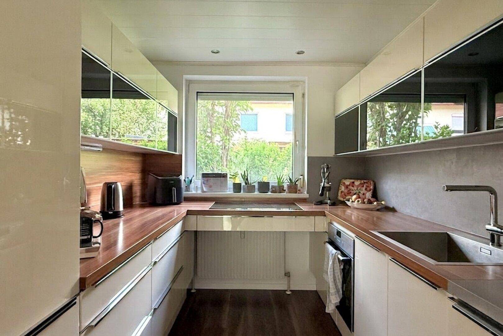 Helle, moderne Küche mit weißen Schränken, Holz-Arbeitsplatten und Fenster.