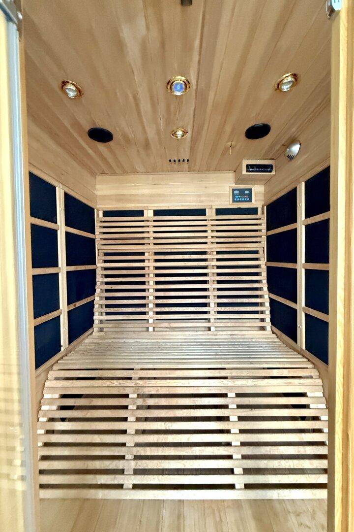 Innenansicht der Sauna mit Holzlattenbänken und integrierten Heizelementen.