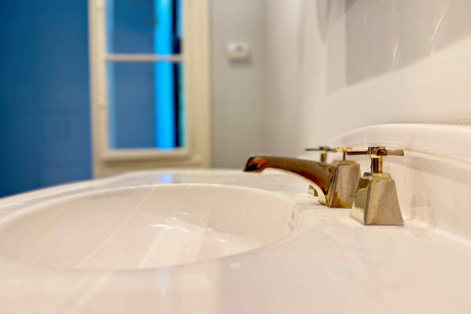 Nahaufnahme eines eleganten Wasserhahns am Waschbecken mit Fenster im Hintergrund.