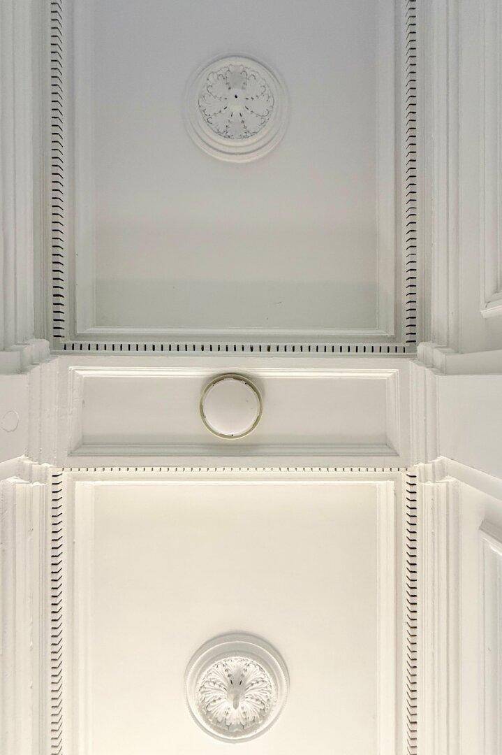 Detailaufnahme einer kunstvoll verzierten Stuckdecke mit klassischen Ornamenten.