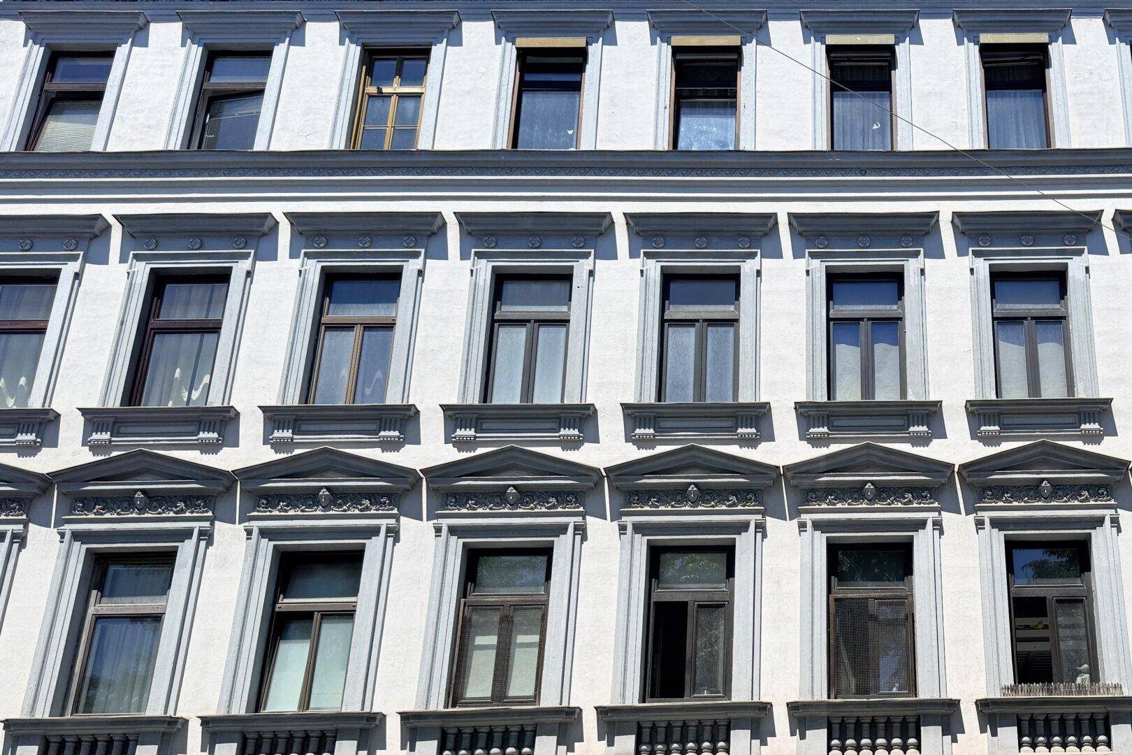Fassade eines Altbaus mit vielen Fenstern und klassischen architektonischen Details.