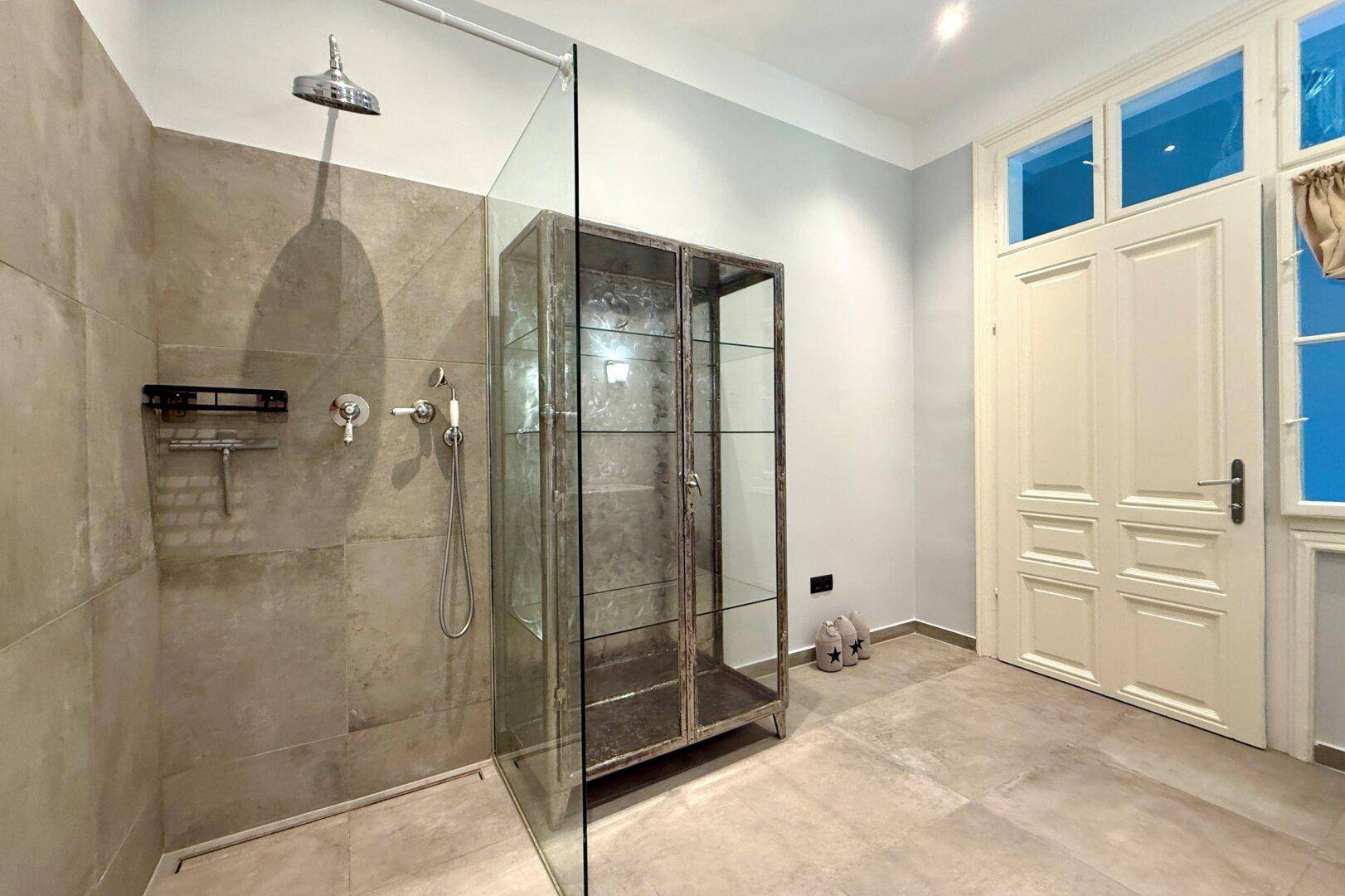 Modernes Badezimmer mit begehbarer Dusche, Glasabtrennung und einem industriellen Schrank.