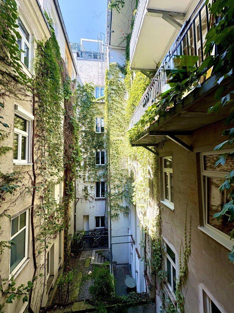 Blick von oben auf den begrünten Innenhof mit Kletterpflanzen an den Gebäudefassaden.