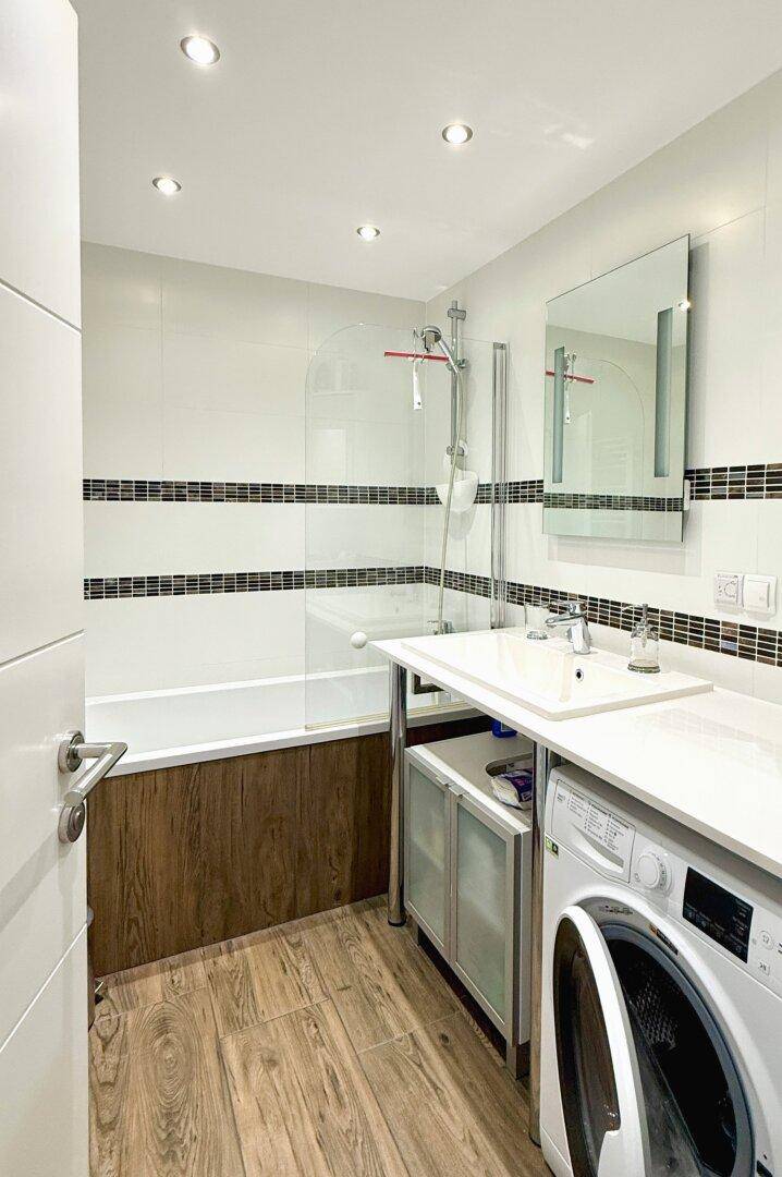 Modernes Badezimmer mit Badewanne, Dusche, Waschbecken und integrierter Waschmaschine.