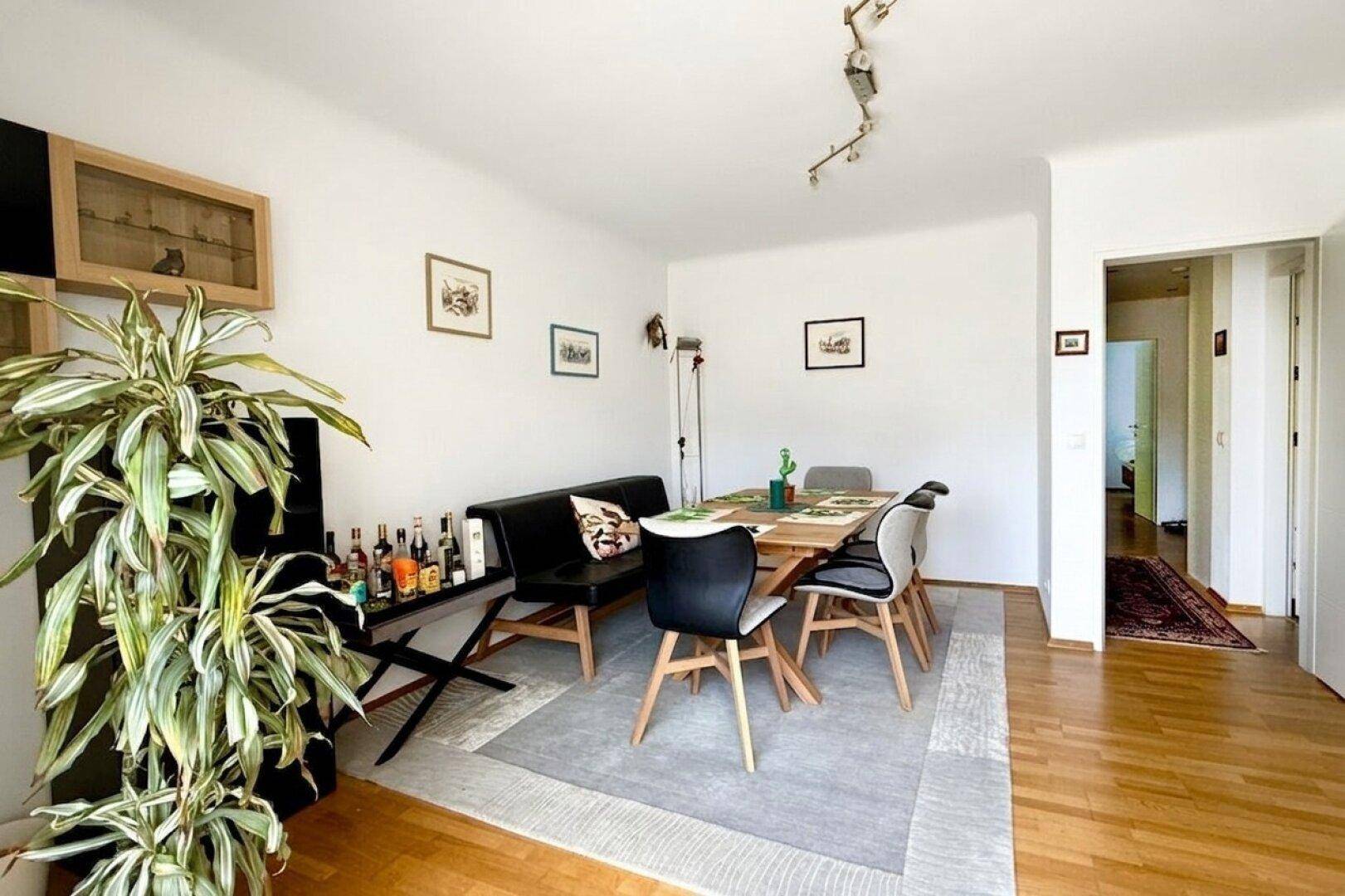 Gemütlicher Essbereich mit Holzboden, modernem Esstisch und Pflanzen als Dekoration.
