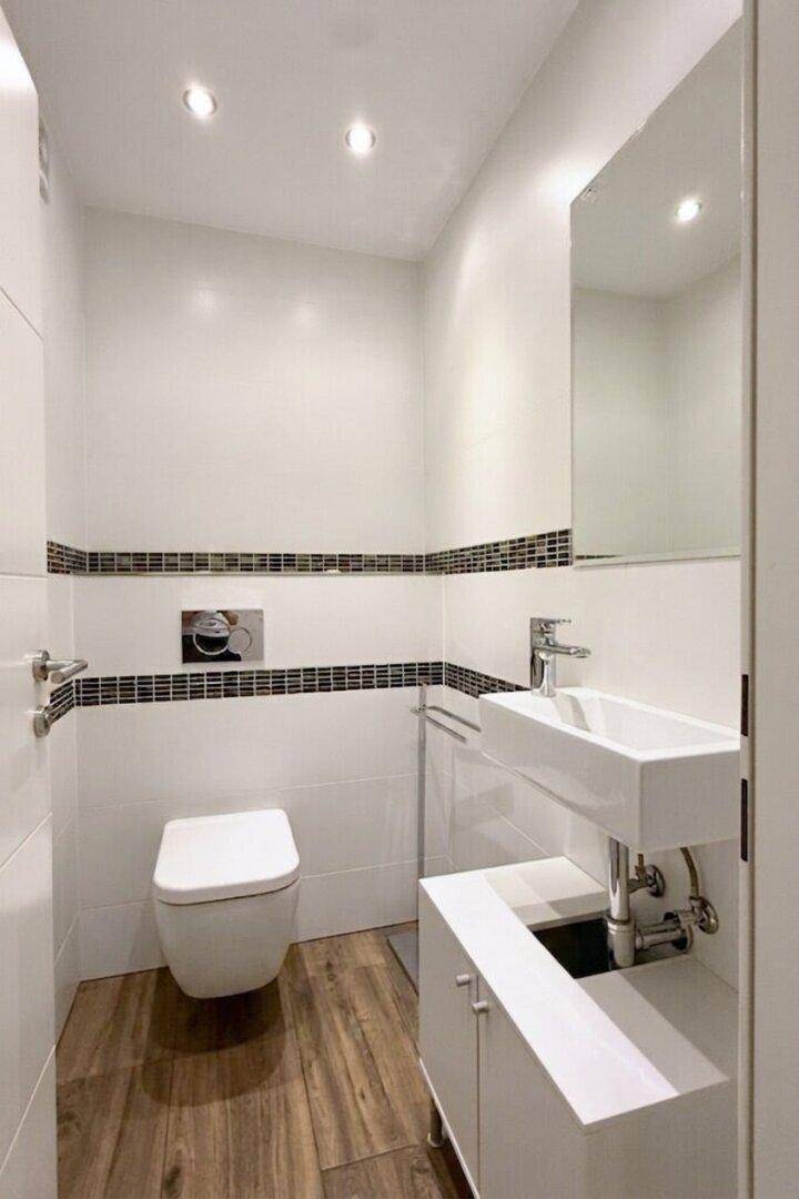 Separates WC mit modernem Wand-WC und kleinem Waschbecken.