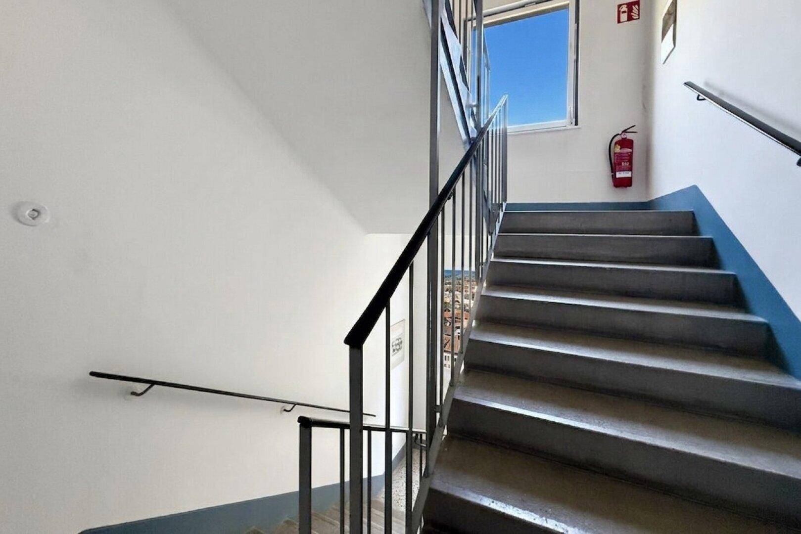 Treppenhaus mit robusten Stufen und Geländer, das zu den oberen Etagen führt.