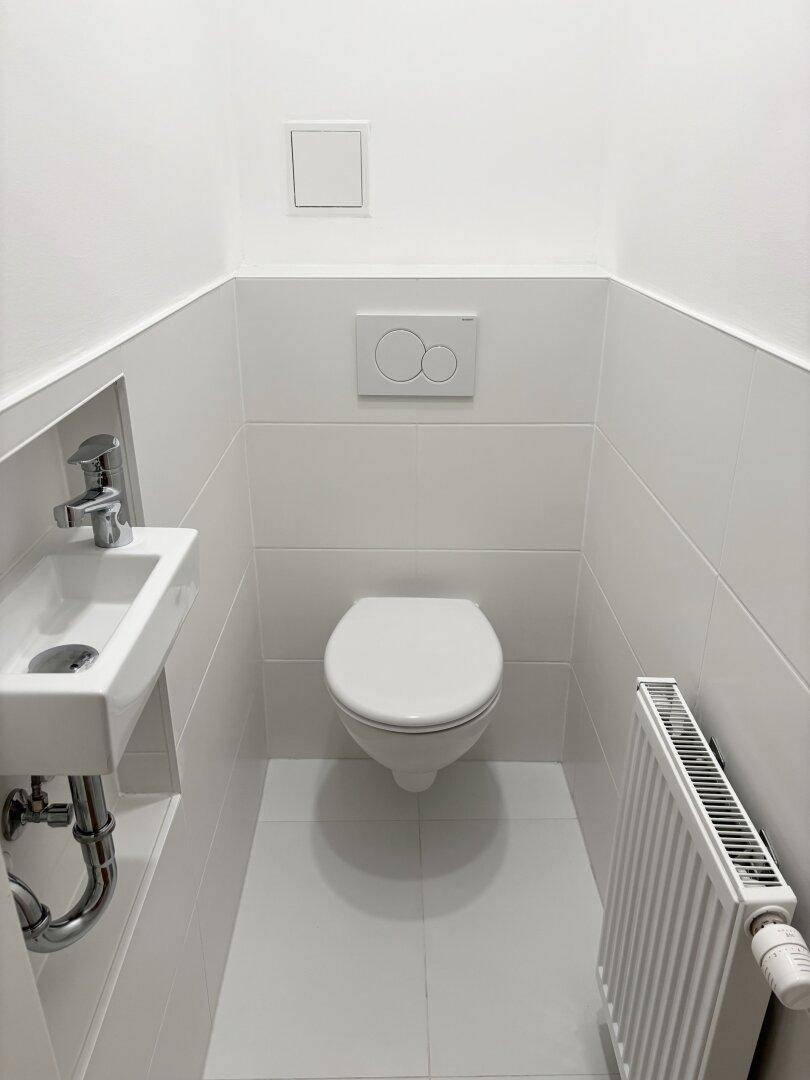 Kompaktes Gäste-WC mit wandhängender Toilette und kleinem Handwaschbecken.