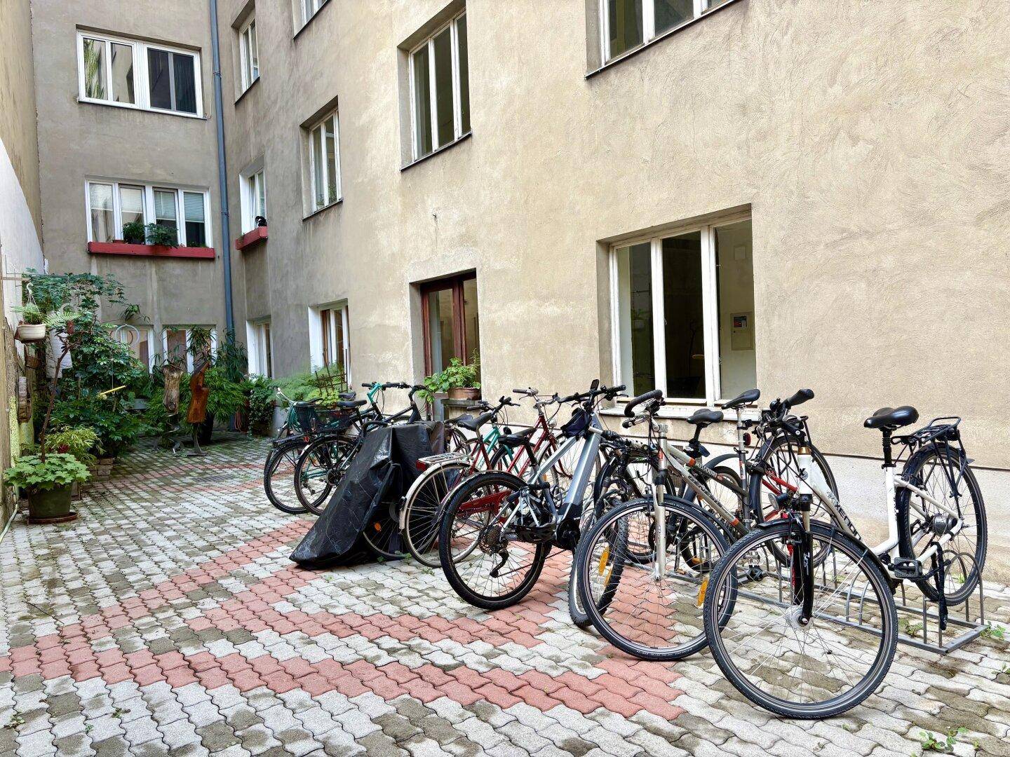 Gepflasterter Innenhof mit Fahrradabstellmöglichkeiten und dekorativen Pflanzen.