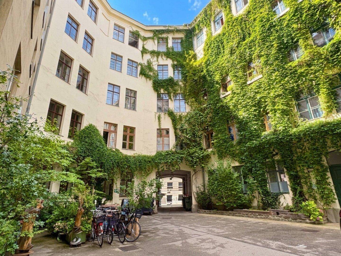 Idyllischer Innenhof mit begrünten Fassaden und Fahrradstellplätzen.
