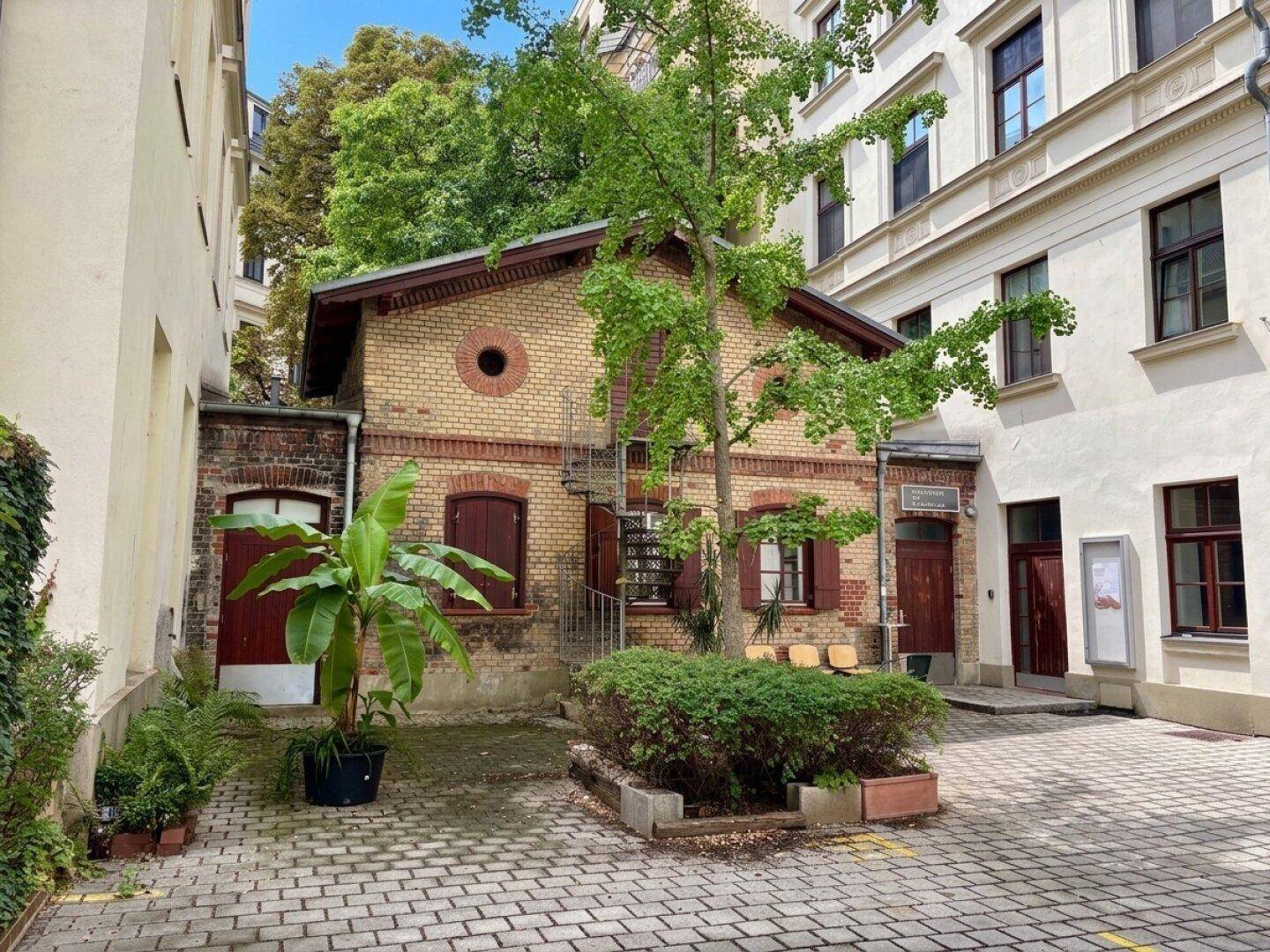 Kleines Gebäude im Innenhof mit gelben Ziegeln und Außentreppe.