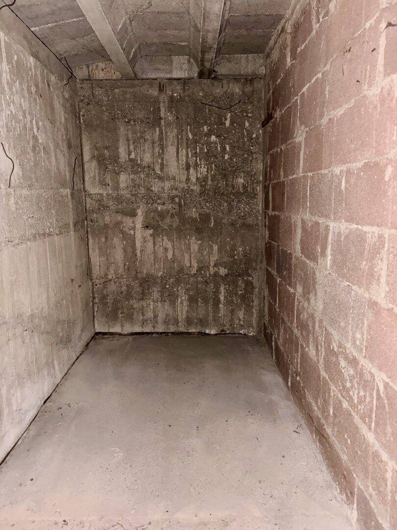 Unfertiger Kellerraum mit Betonwänden und -boden, ideal als Abstellfläche.