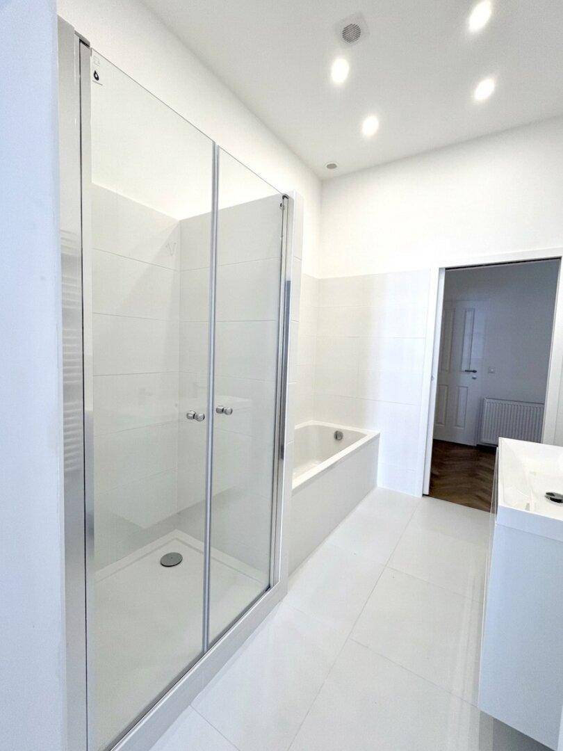 Geräumiges Badezimmer mit moderner Glasduschkabine, Badewanne und schwebendem Waschtisch.