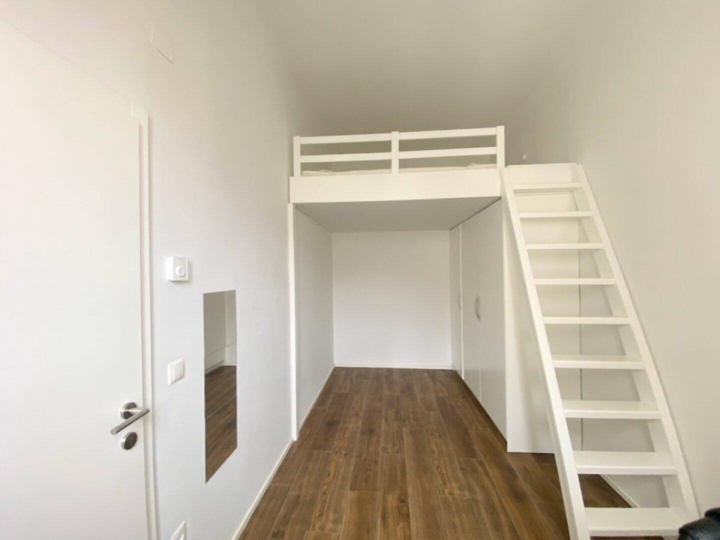 Helles Zimmer mit Hochbett und Leiter, ideal als Schlaf- oder Arbeitsbereich, auf dunklem Holzfußboden.