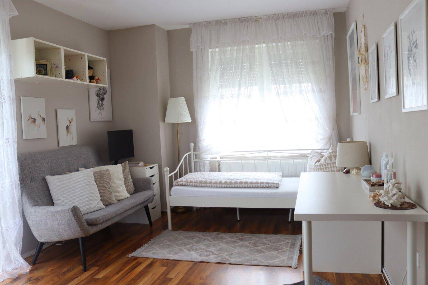 Helles Schlafzimmer oder Gästezimmer mit Einzelbett, Schreibtisch und einem kleinen Sofa.