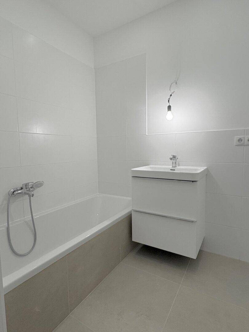 Modernes Badezimmer mit Badewanne, Waschbecken und weißen Fliesen an den Wänden.