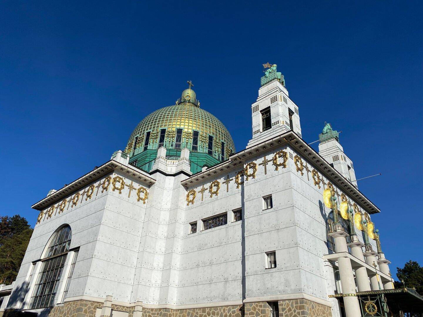 Historische Kirche mit goldener Kuppel und kunstvollen Verzierungen unter blauem Himmel.