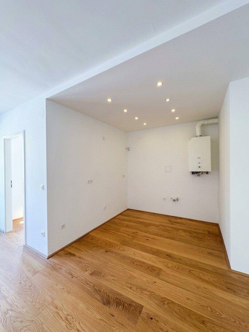 Bereich für eine Küche mit vorbereiteten Anschlüssen und Einbaustrahlern an der Decke.