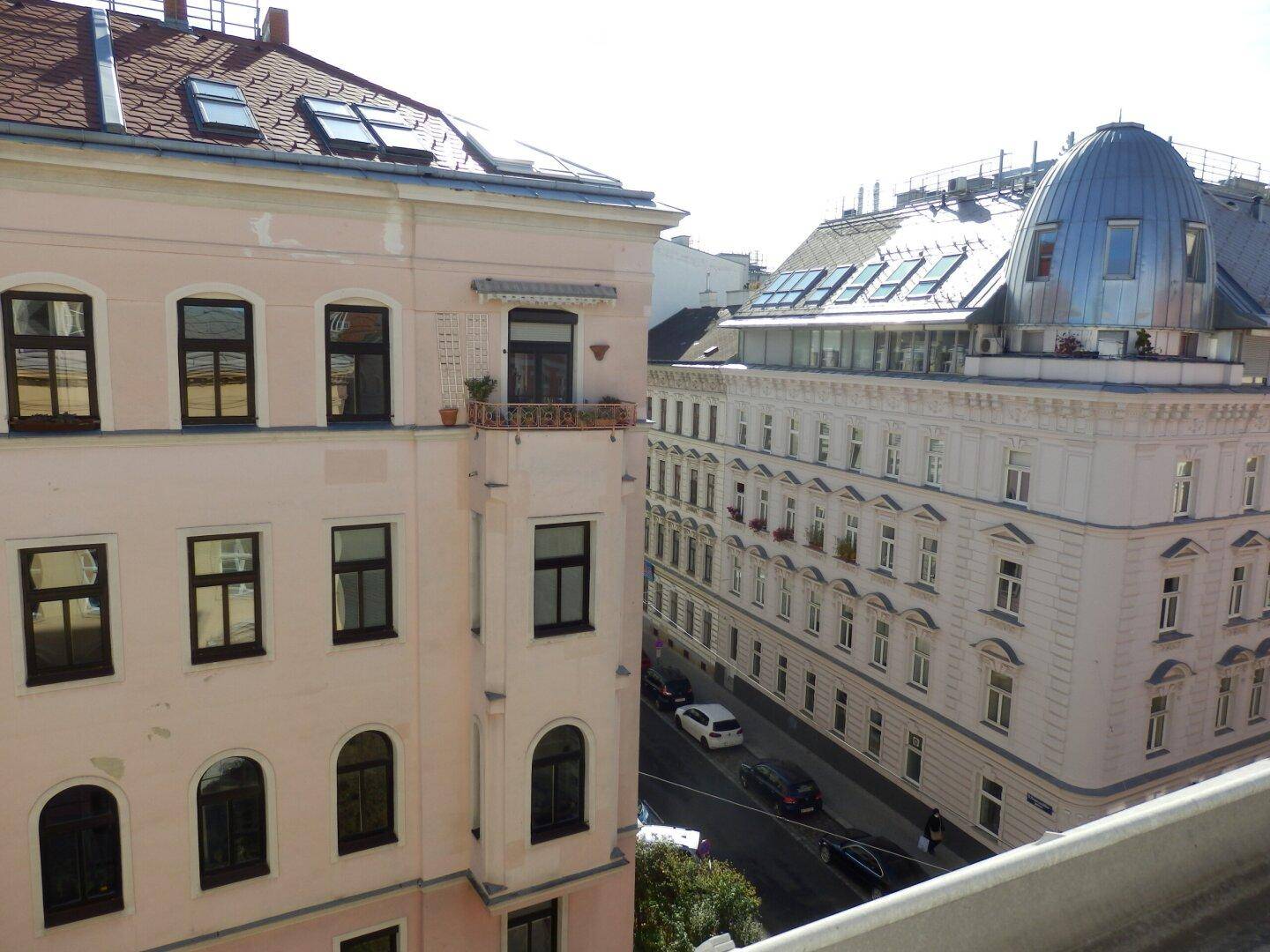 Blick von oben auf die umliegenden Gebäude und die belebte Straße mit historischer Architektur.