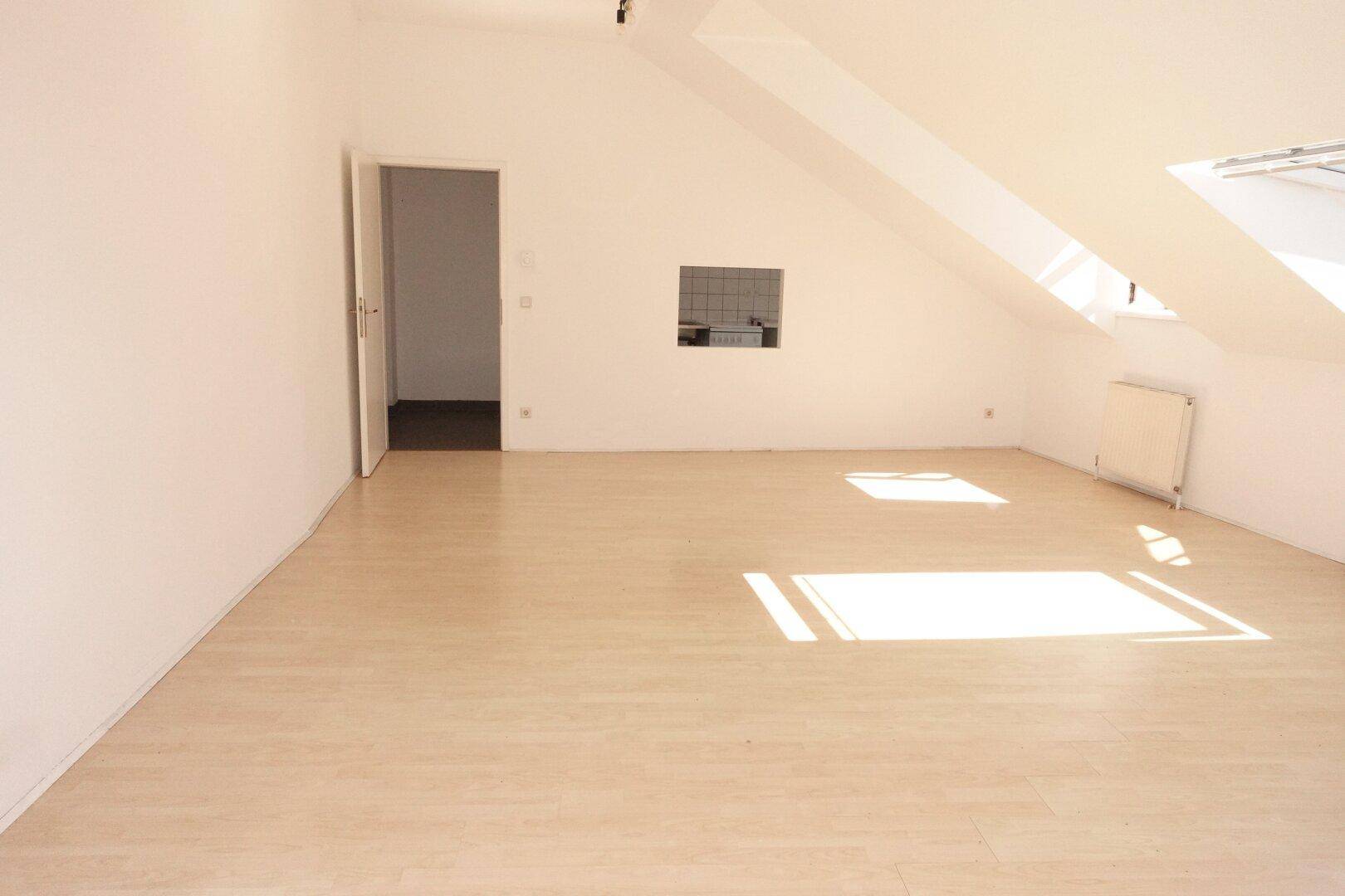 Geräumiger Dachbodenraum mit schrägen Wänden, Dachfenster und hellem Laminatboden, bietet vielseitige Nutzungsmöglichkeiten.