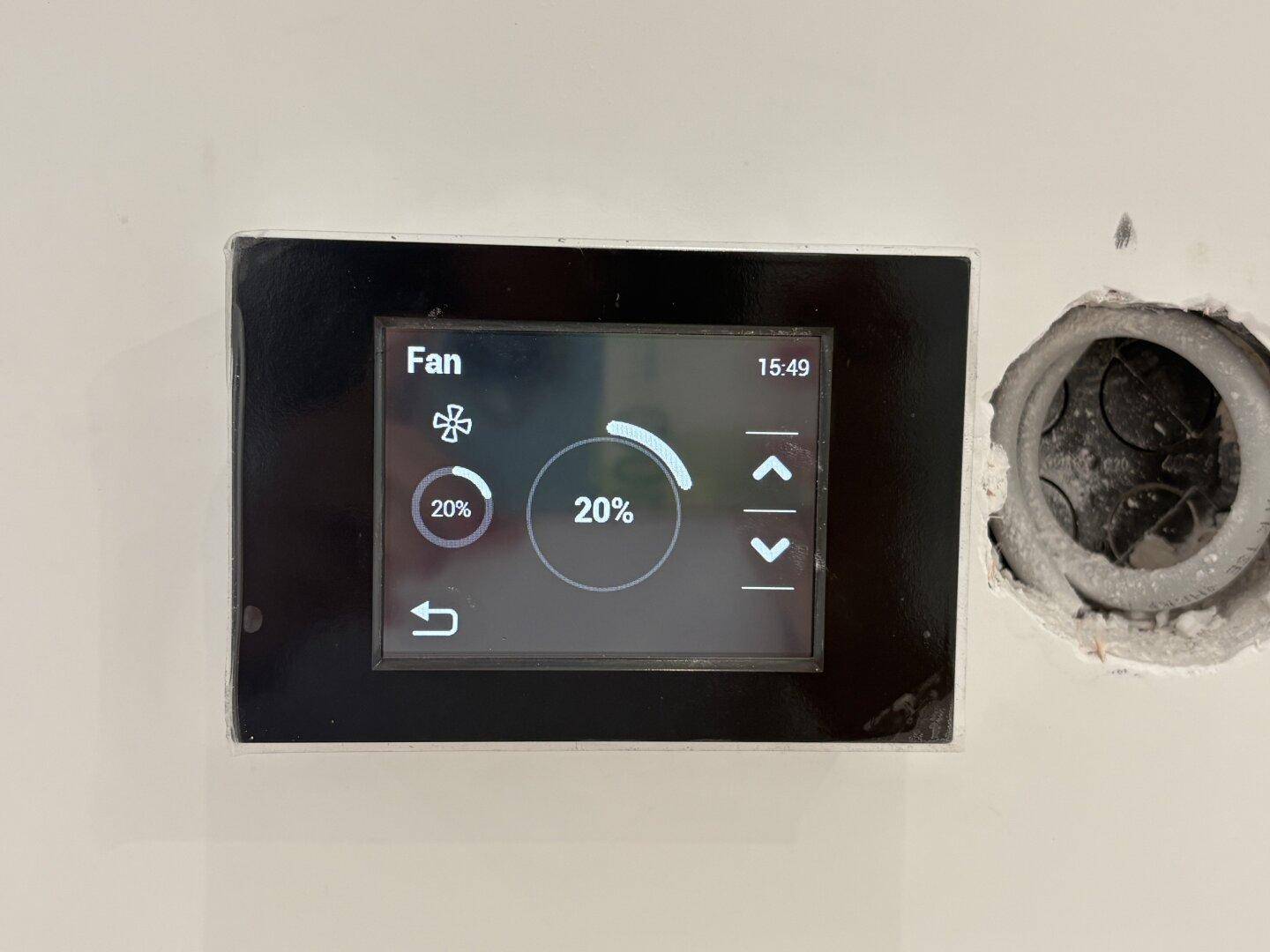 Wandmontiertes digitales Bedienfeld zur Steuerung der Lüftung oder Klimaanlage in einem modernen Raum.