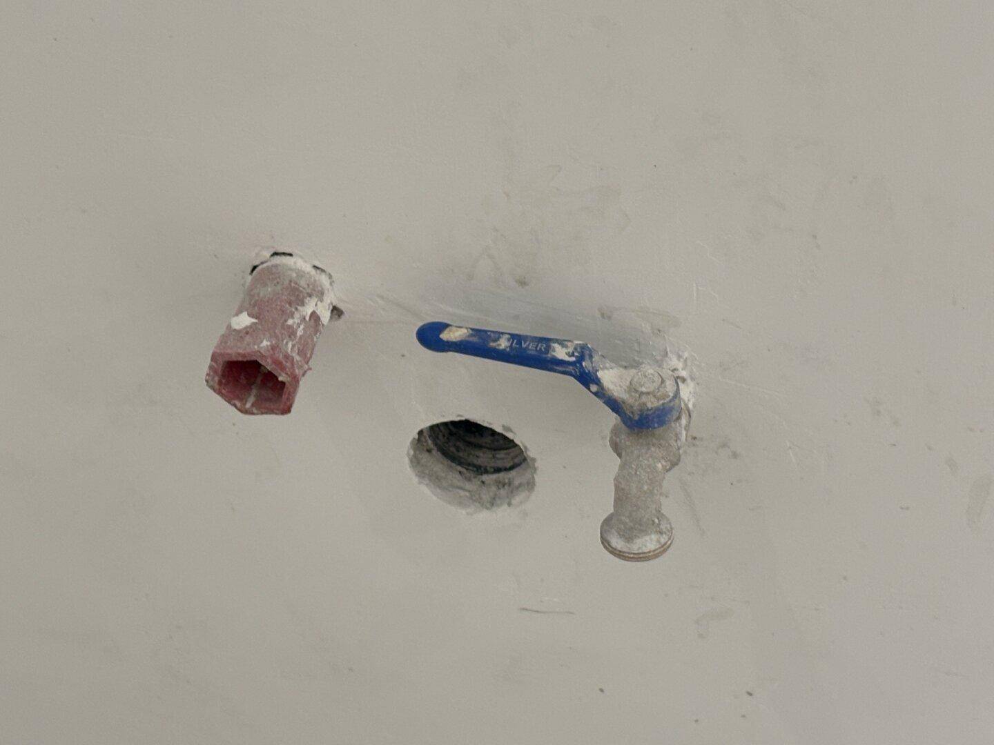 Freiliegende Wasseranschlüsse und ein Absperrventil in einer Wand, bereit für die Installation eines Geräts.