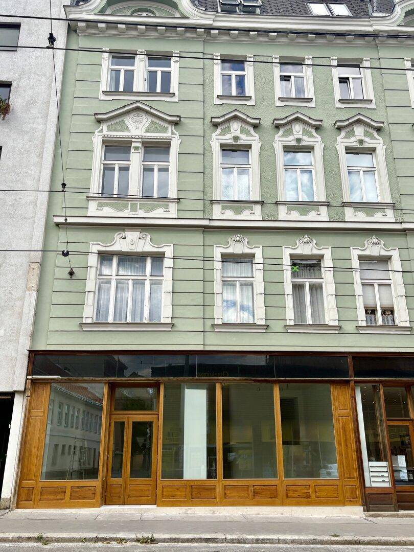Prächtige historische Fassade eines Gebäudes mit grüner Farbgebung und kunstvollen Fensterrahmen.
