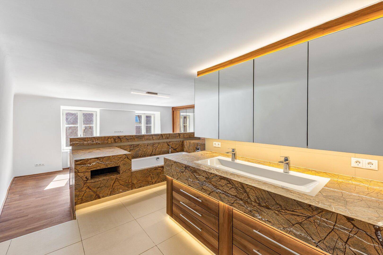 Helles, modernes Badezimmer mit Doppelwaschbecken, Stein-Arbeitsplatten und Badewanne.
