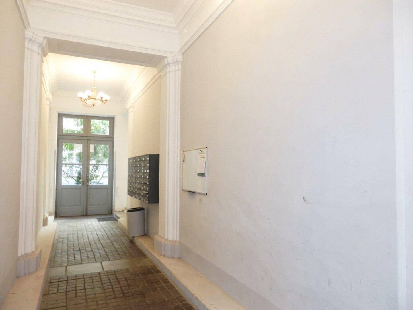 Eingangsbereich eines Gebäudes mit Briefkästen und einer Doppeltür zum Außenbereich.